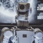 The upper half of a robotic figure looking toward the camera