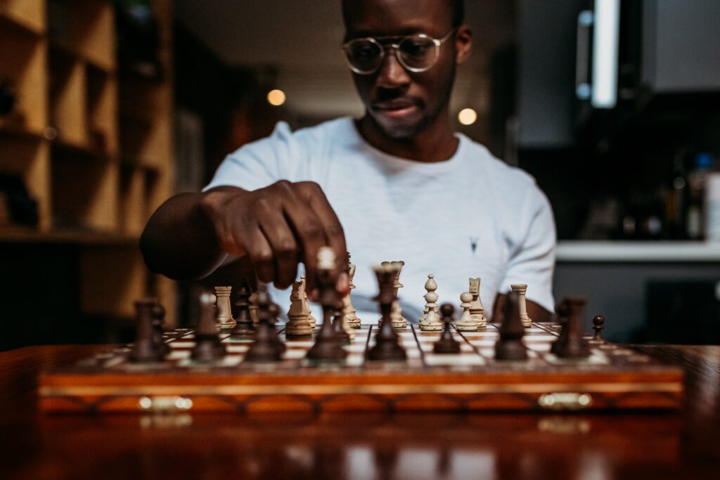 A man sitting at a chessboard, moving a piece.