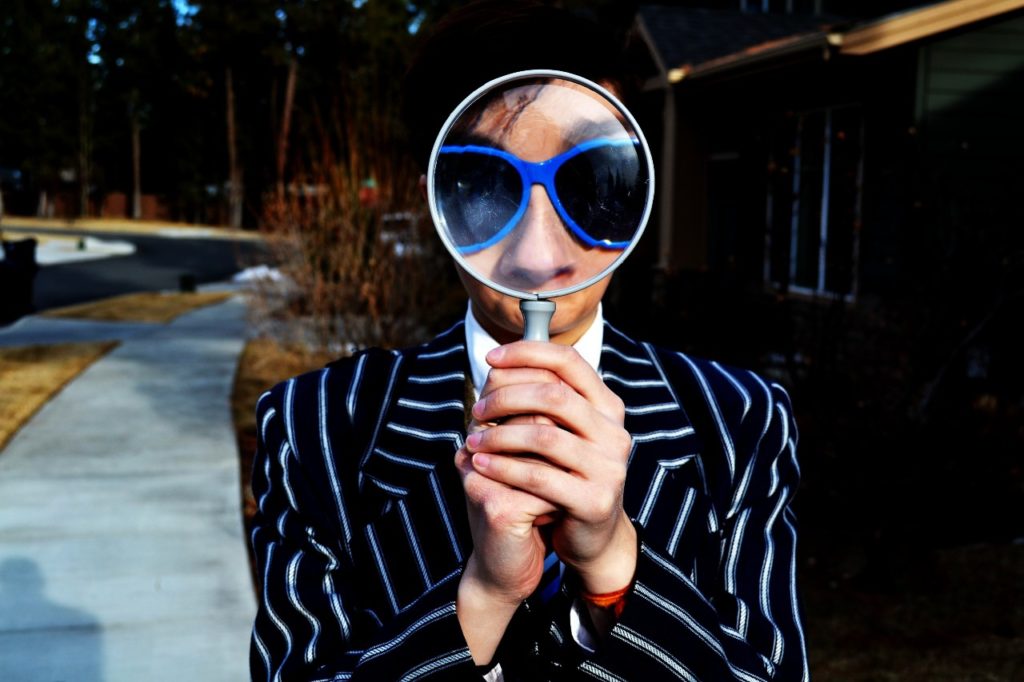 A person holding a magnifying glass to their face.
