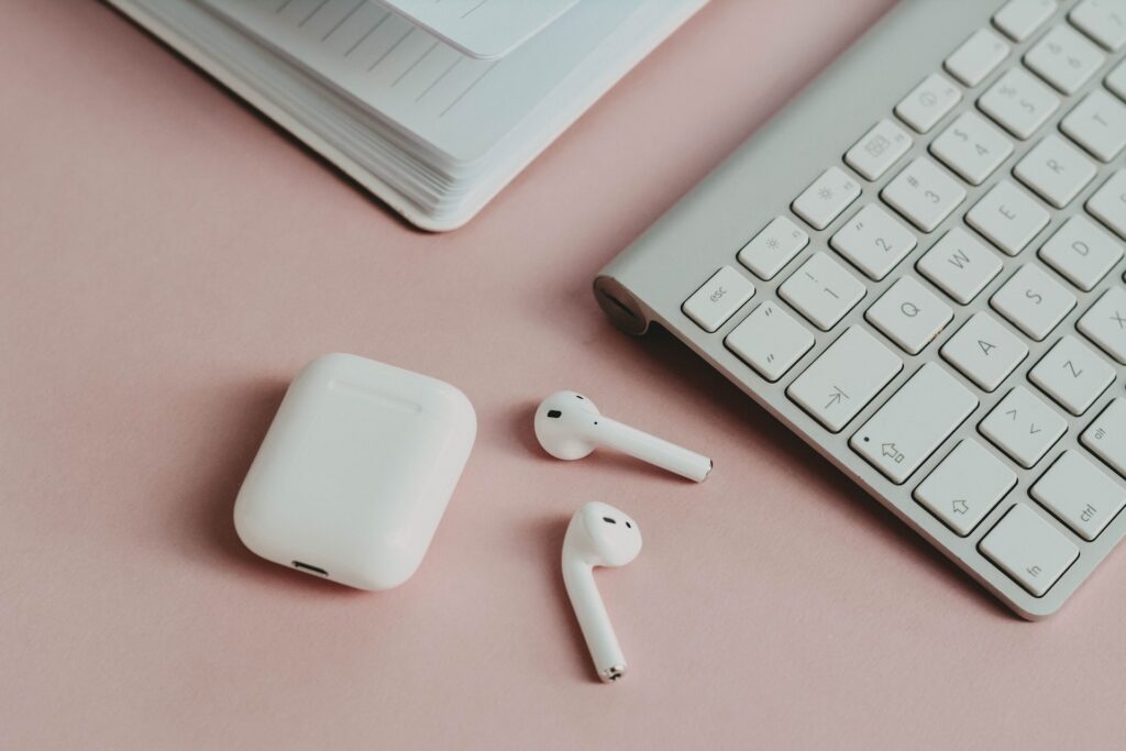 Apple AirPods laying on a surface next to an Apple keyboard