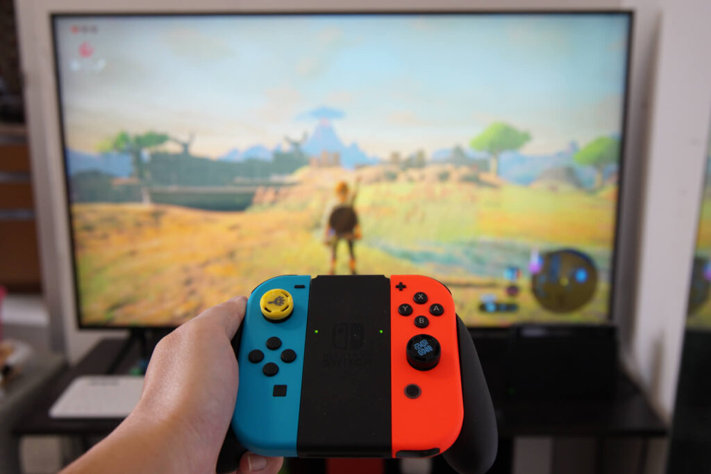 a set of joy-cons with a TV playing the legend of zelda breath of the wild