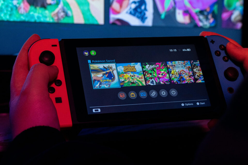 person holding nintendo switch showing games in menu