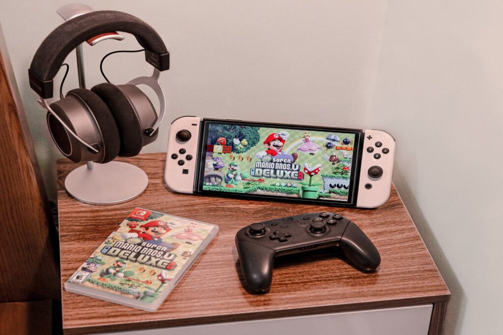 Nintendo Switch on a table next to a controller and a pair of headphones