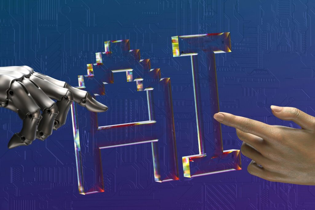 A robotic hand and a human hand pointing toward the letters AI