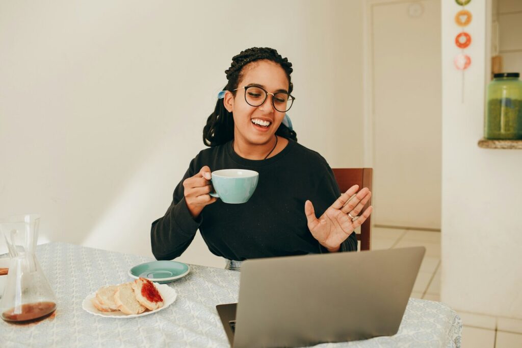 A woman waving to her laptop's camera