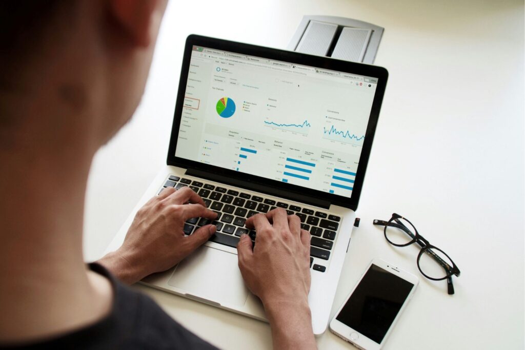 Person using a laptop to review a business analytics dashboard with colorful charts and graphs.